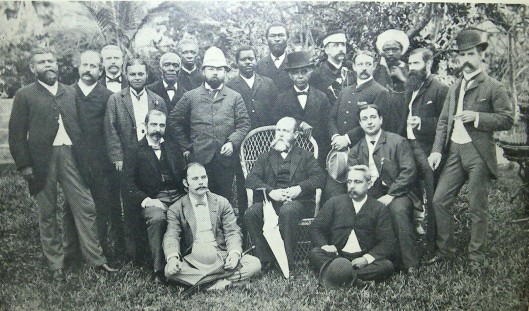 This photograph from the Colonial Records Office depicts the Senior Service, comprised of high-ranking colonial officials in Sierra Leone. The group was awaiting the arrival of Governor Sir Samuel Rowe who had returned to England earlier that year. Seated in the middle with the umbrella is Acting Governor Francis F. Pinkett who was the Chief Justice.